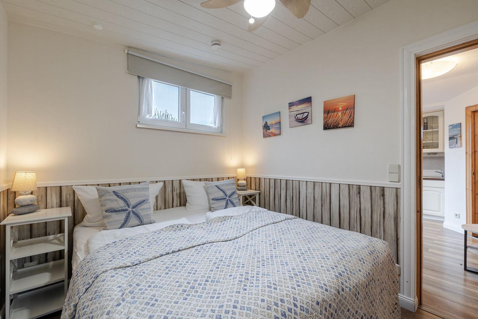 Schlafzimmer mit Bett, Nachttischen und Wandbildern