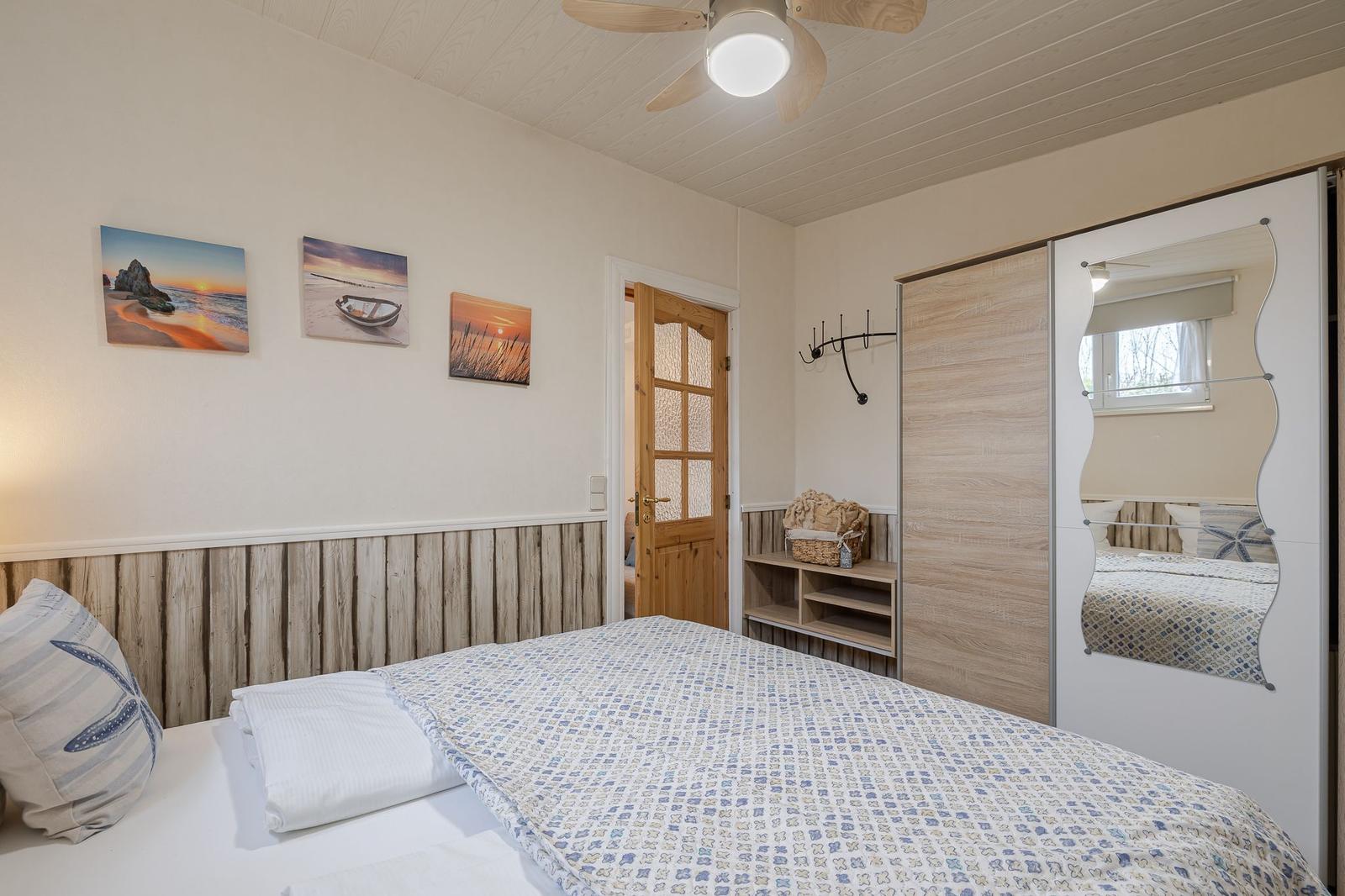 Schlafzimmer mit Bett, Kleiderschrank und Wandbildern