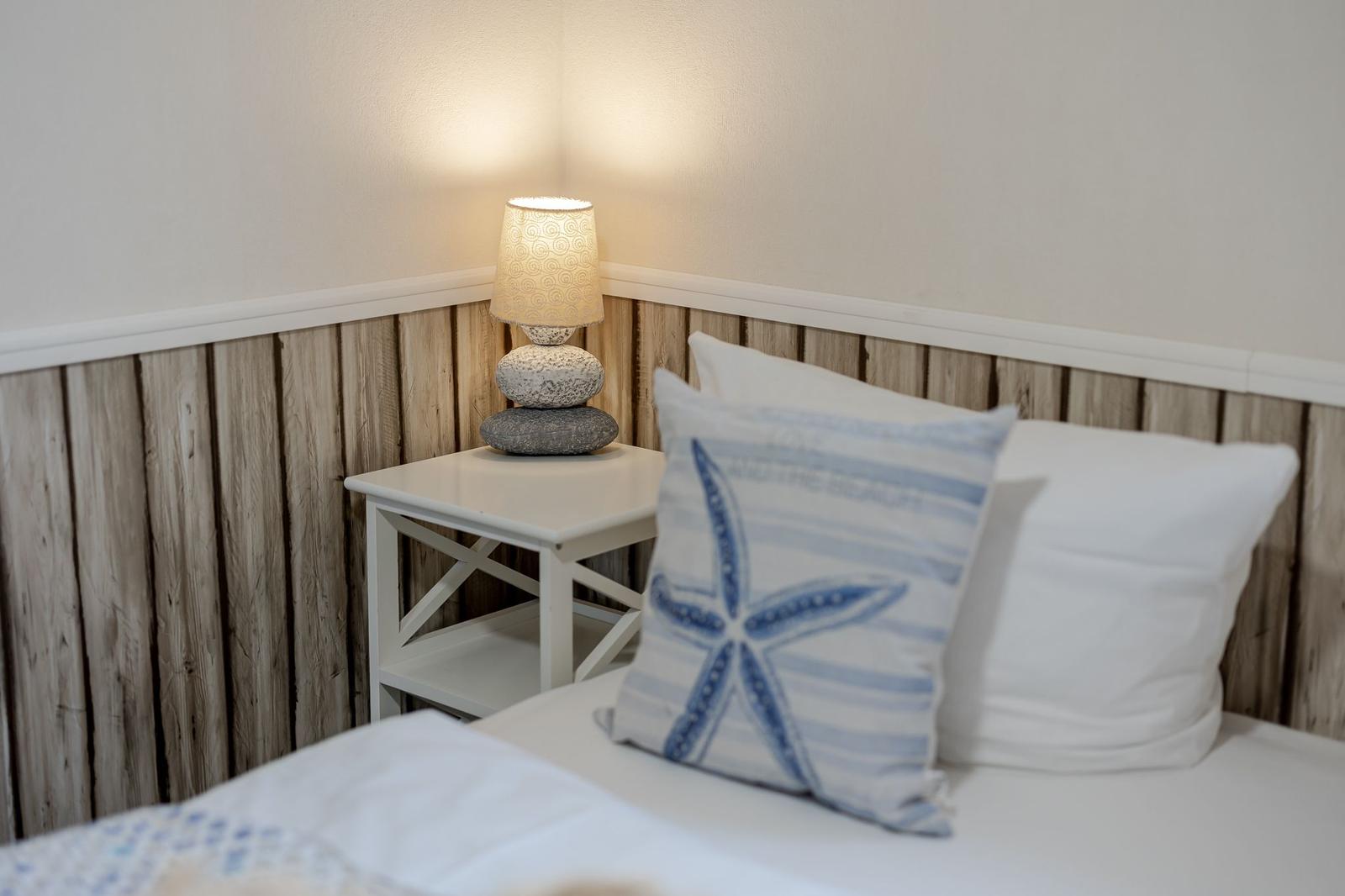 Bettkante mit Kissen und Nachttisch mit Lampe.