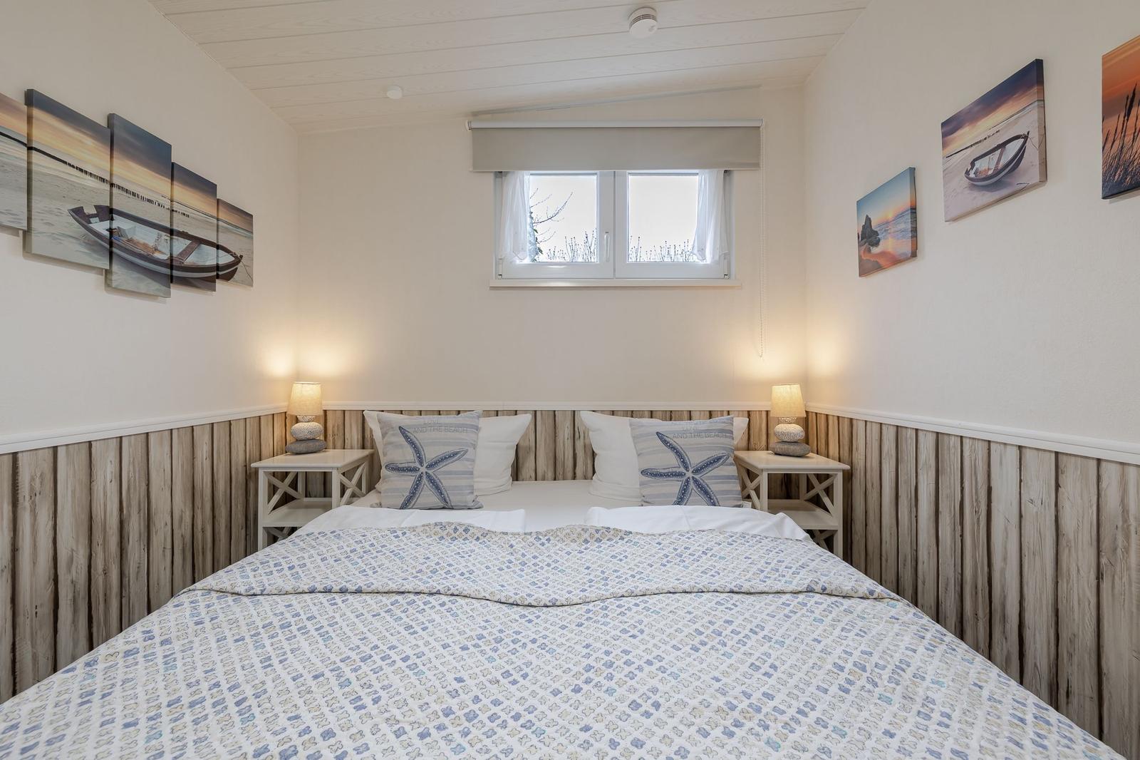 Schlafzimmer mit Bett, Nachttischen und Wandbildern an den Wänden.