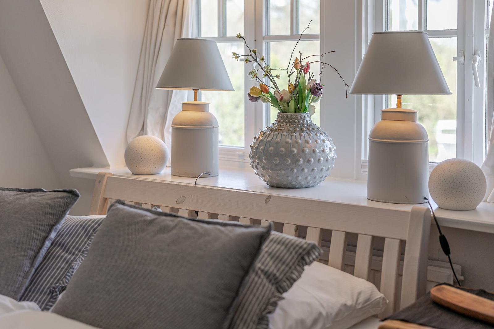 Bedroom with bed, window, and decorative lamps on windowsill.