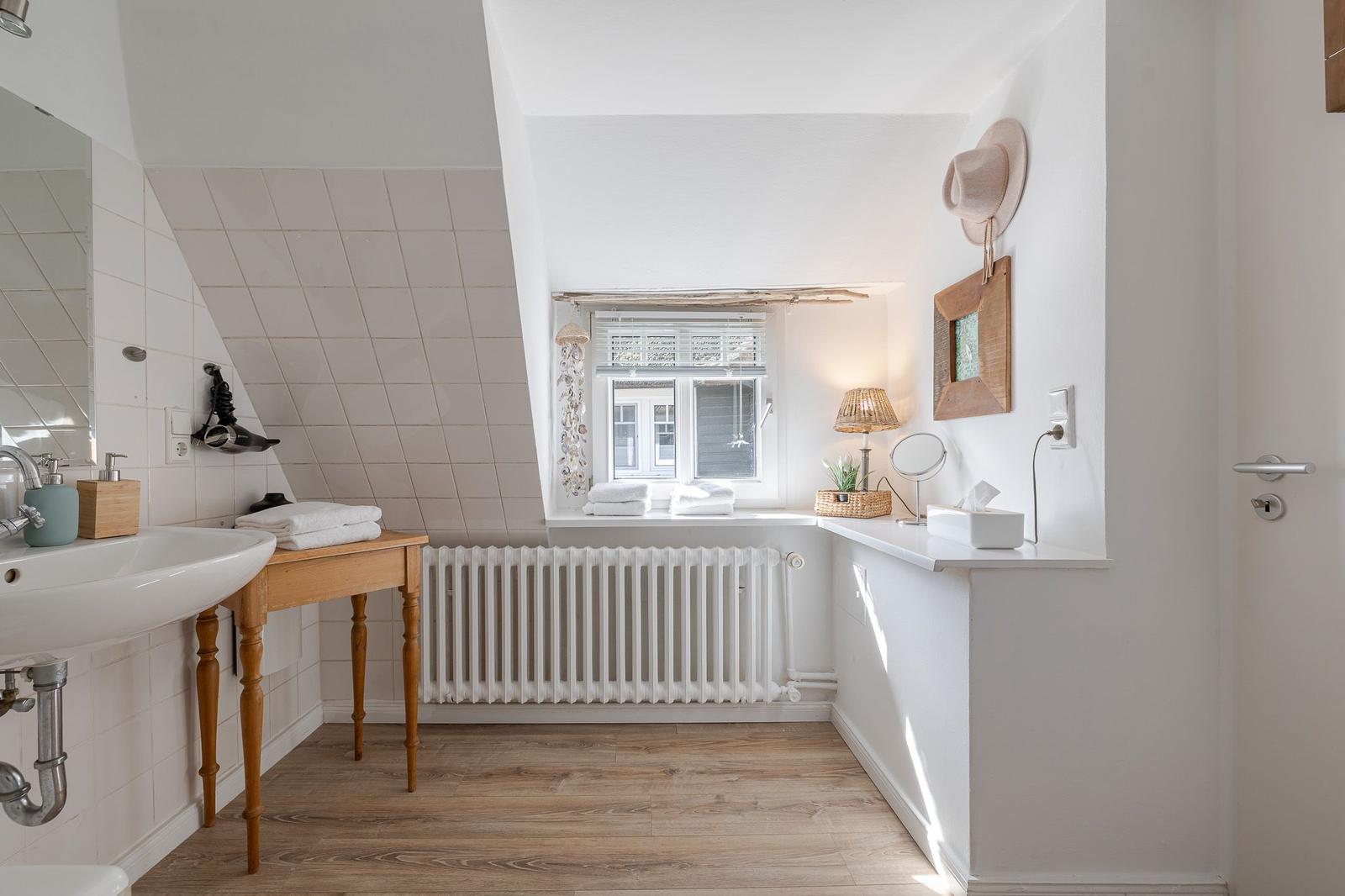Bathroom with wooden floor, sink, and window