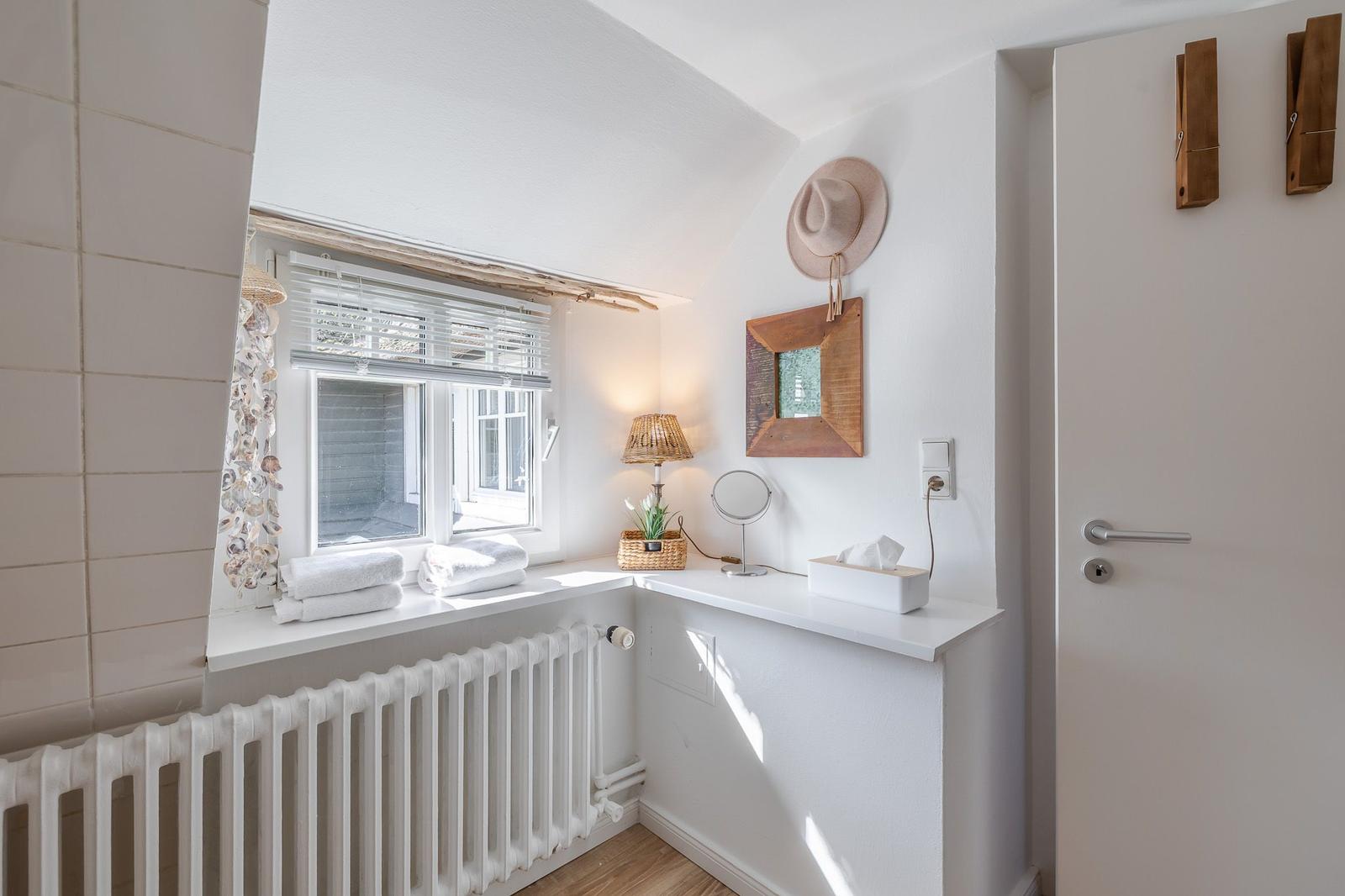 Bathroom with window, radiator, and decorative items on the wall.