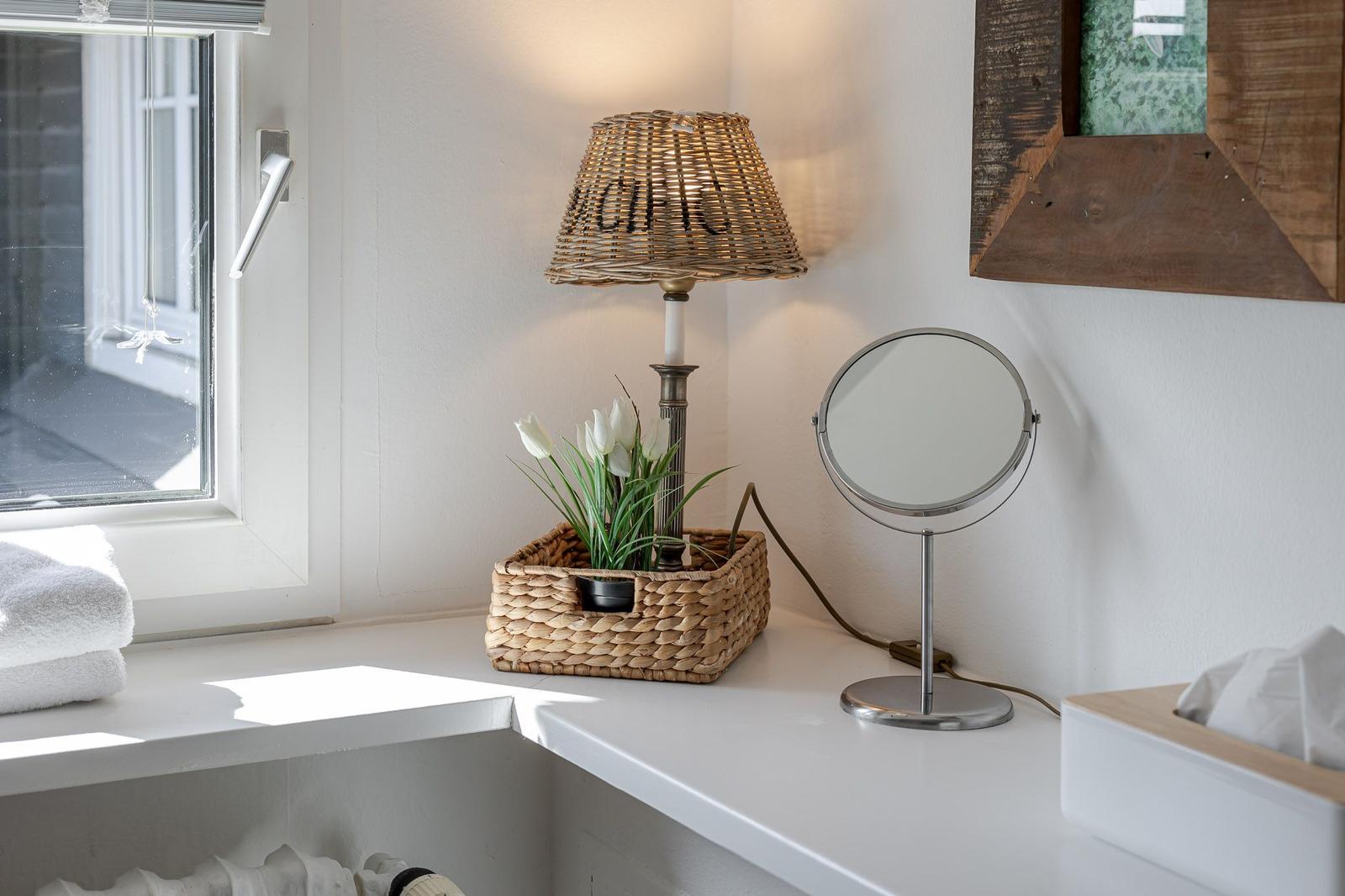 Bathroom with window, lamp, mirror, and flowers in basket