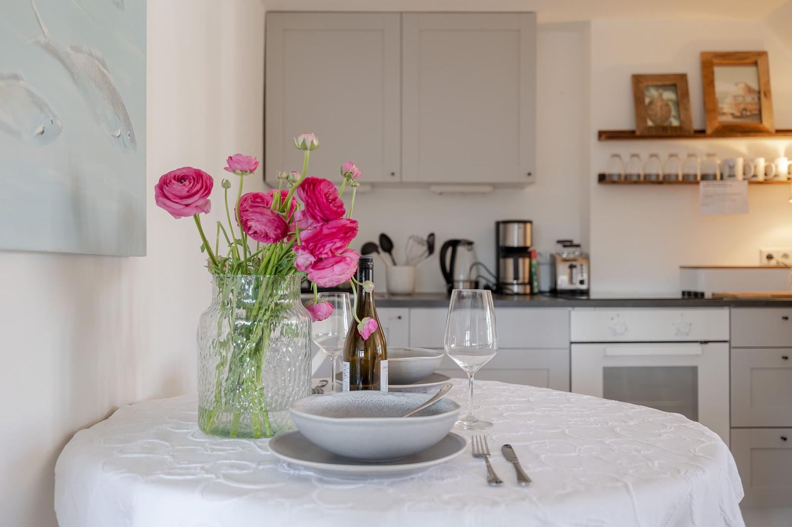 Table with flowers, dishes, and bottle in kitchen