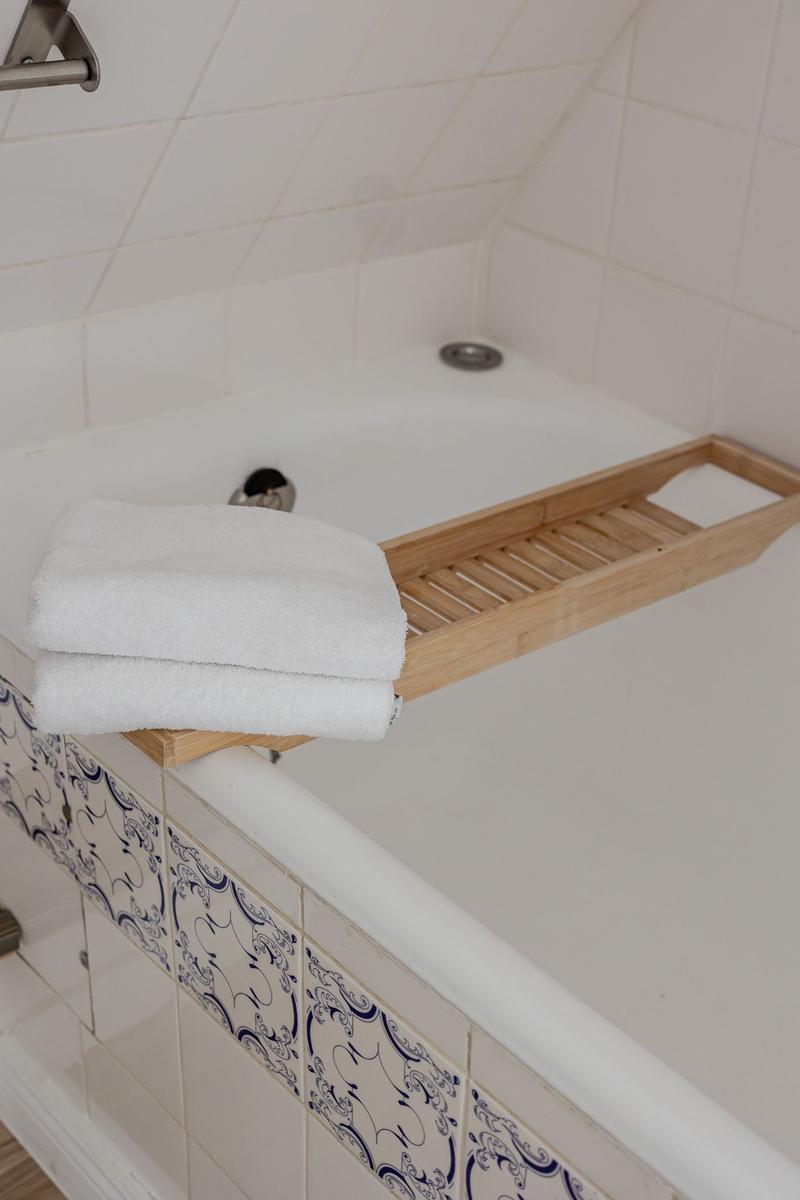Bathtub with wooden tray and folded white towels.
