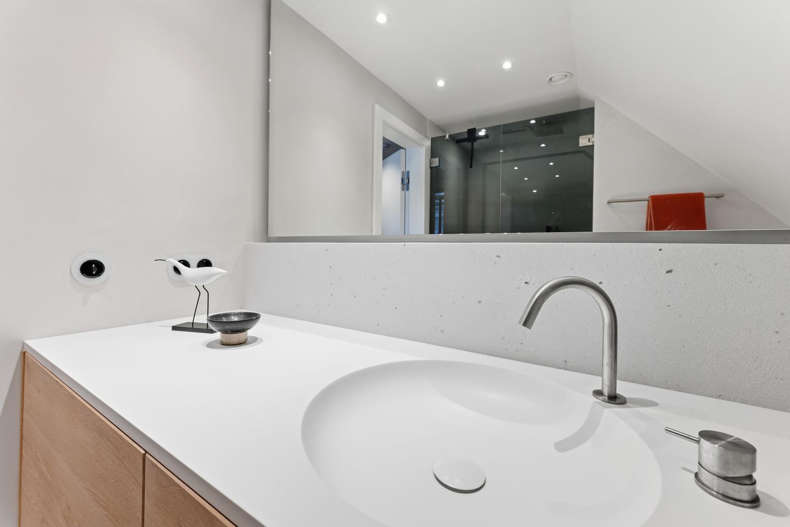 Badezimmer mit Waschbecken, Spiegel und Dusche