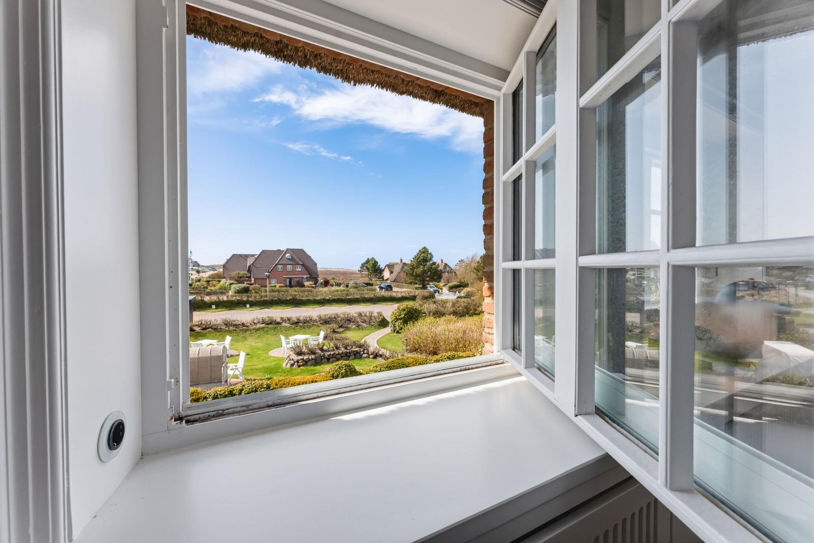 Weitblick aus dem Fenster auf grünen Garten und Ferienhaus.