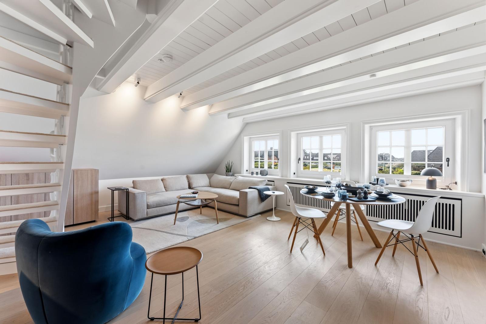 Wohn- und Essbereich mit Sofa, Tisch und Stühlen unter hohen Decken.