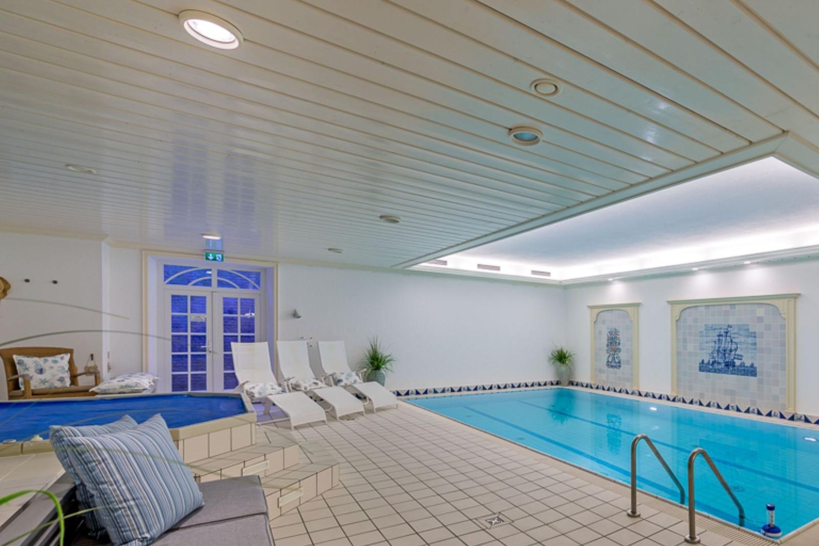 Indirektes Licht erhellt den Poolbereich mit Liegestühlen und Wandbildern.
