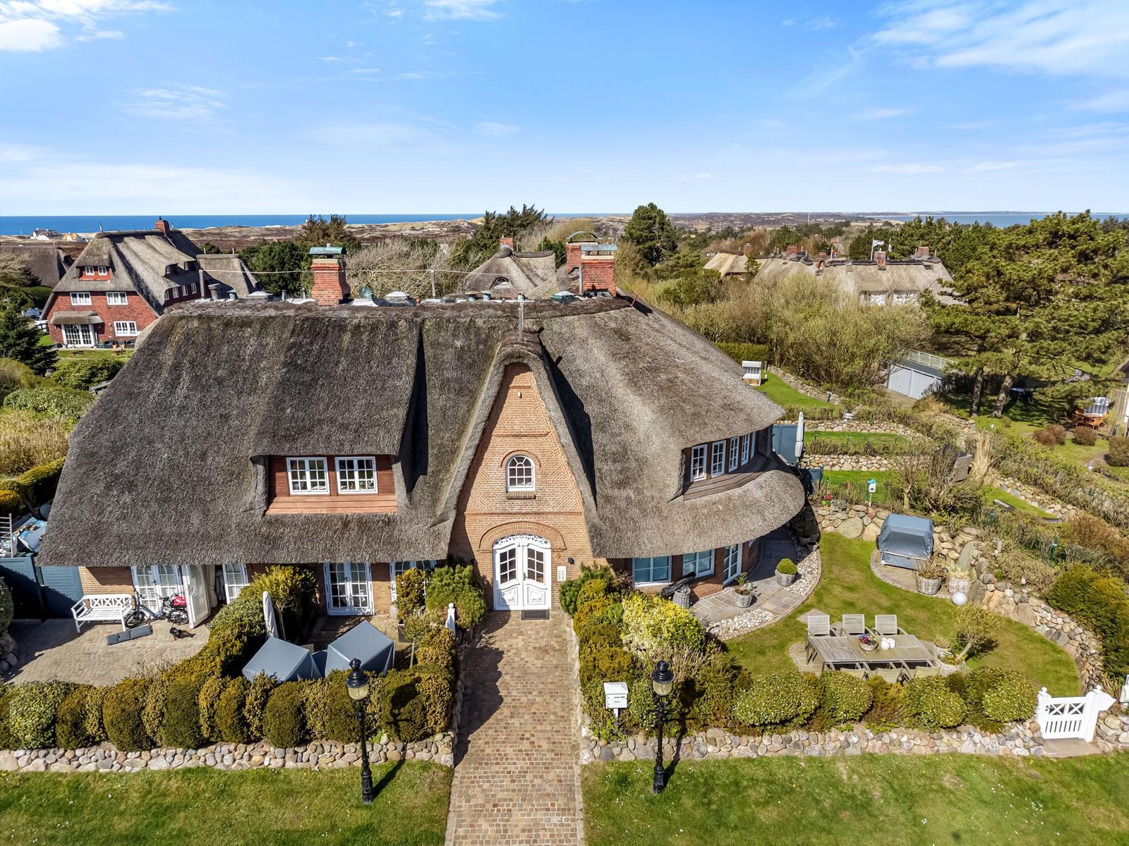 Dorfhaus mit Strohdach, Garten und Blick aufs Meer.