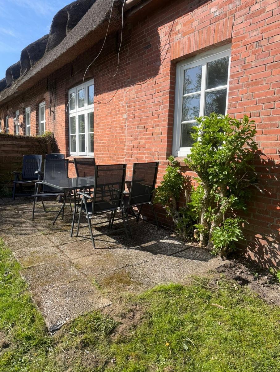 Roter Backsteinbau mit Gartenbereich und Sitzgruppe.
