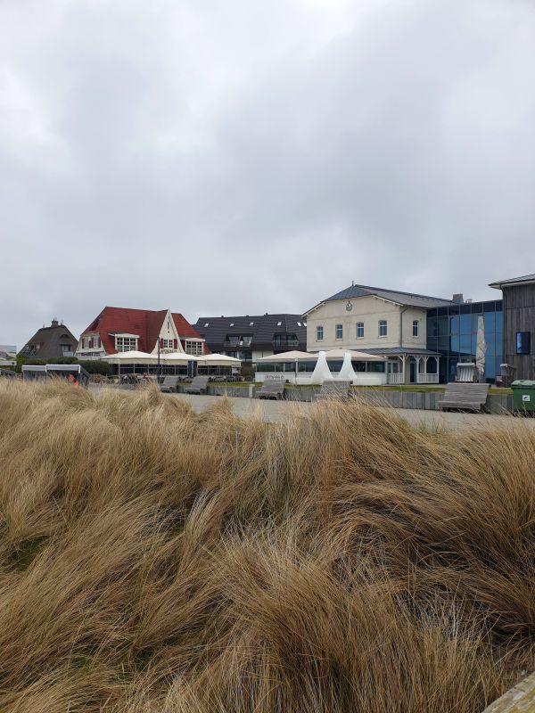 Strandpromenade mit Hotels und Dünenvegetation im Hintergrund.