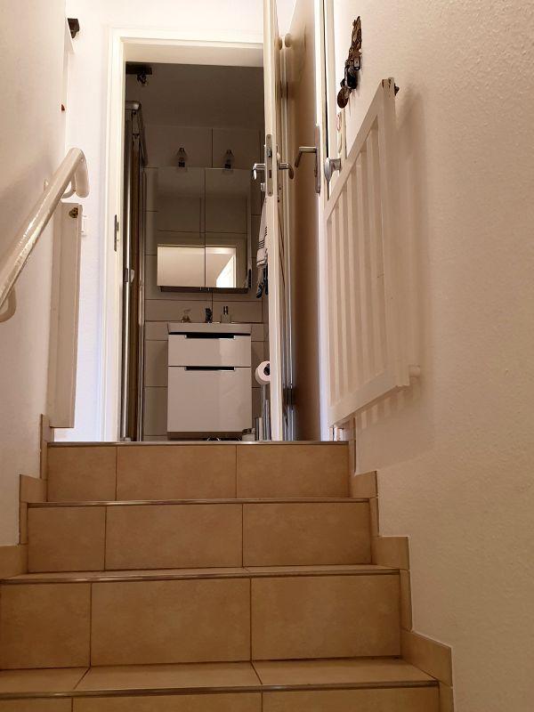 Treppe führt zu einem Badezimmer mit Waschbecken und Spiegel.