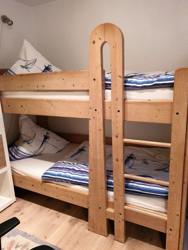 Holz-Etagenbett mit Matratzen und Bettwäsche mit Segelbootmotiv.