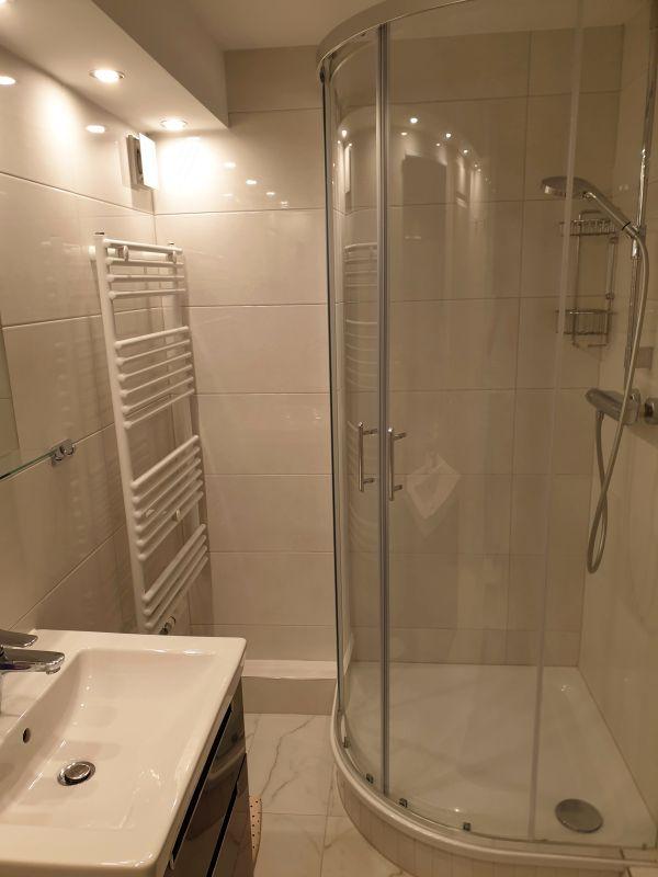 Badezimmer mit Dusche, Waschbecken und Heizkörper