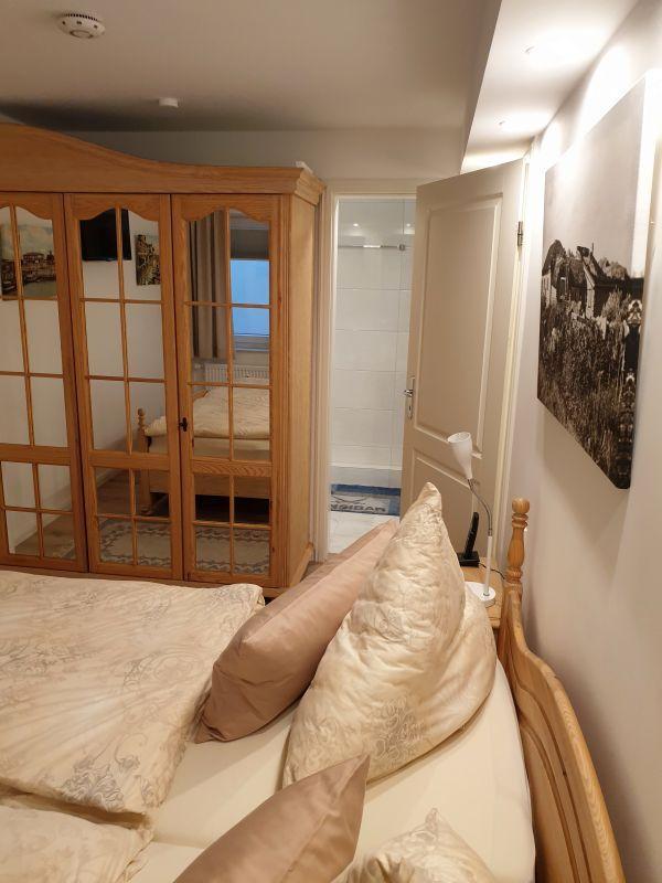 Schlafzimmer mit Holzbett, Spiegelschrank und Badzugang