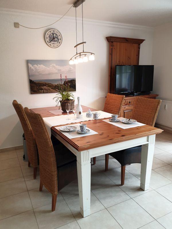 Esstisch mit sechs Stühlen, Wanduhr und Fernseher im Wohnzimmer.