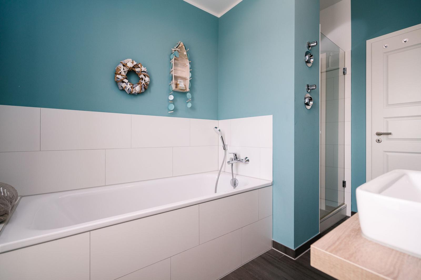 Badezimmer mit Badewanne, Dusche und Waschbecken. Wandfarbe türkis, dekorative Wandobjekte.
