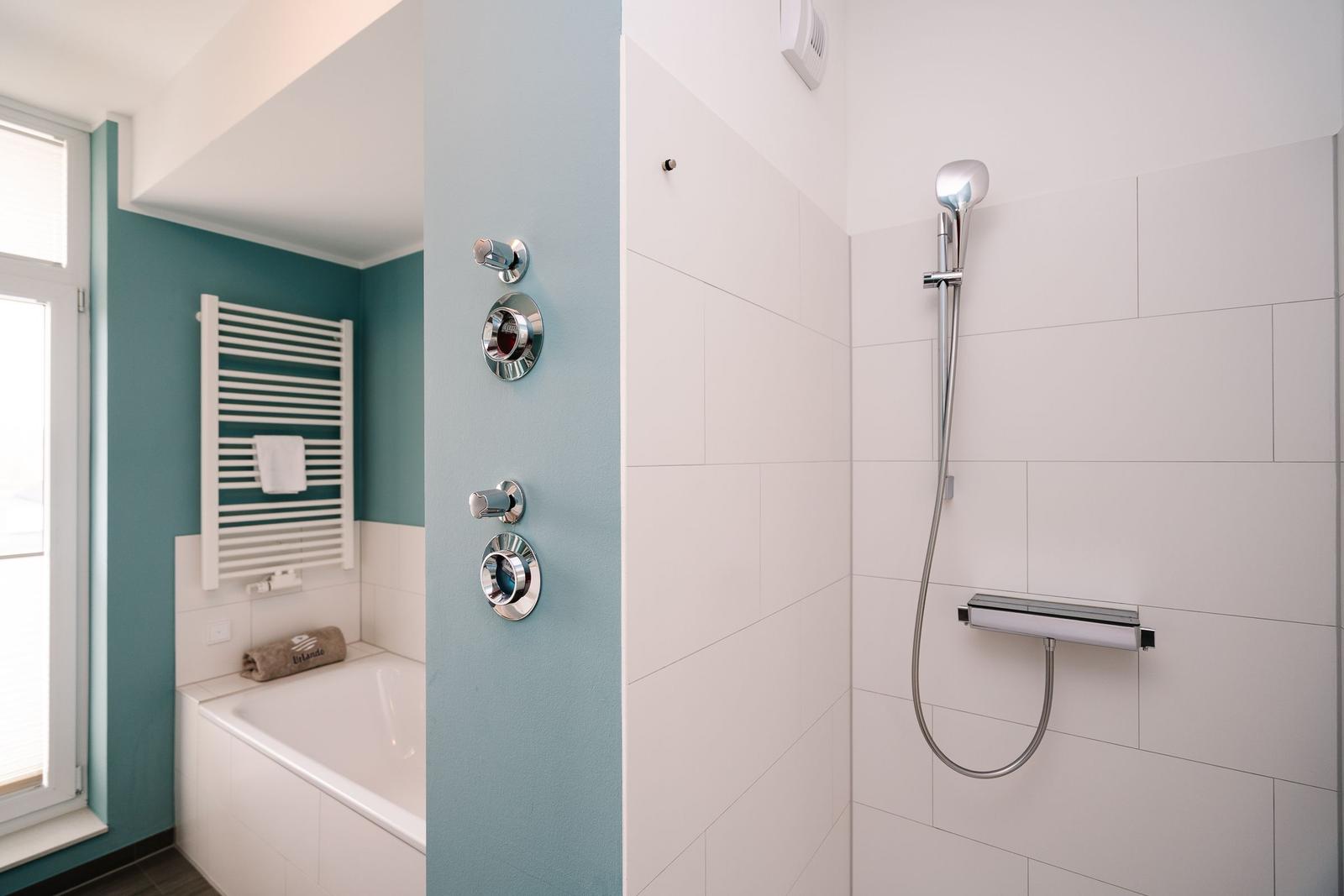 Dusche mit Duschbrause und Whirlpoolbad mit Heizkörper
