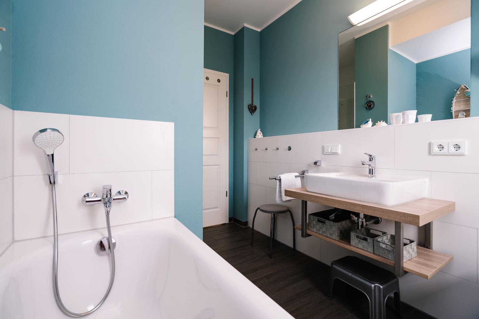 Badezimmer mit Badewanne, Duschkopf, Waschbecken und Spiegel