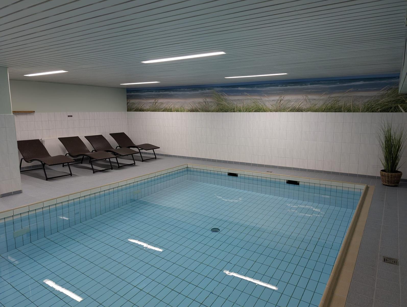 Innere Schwimmhalle mit Liegestühlen und Strandbildwand
