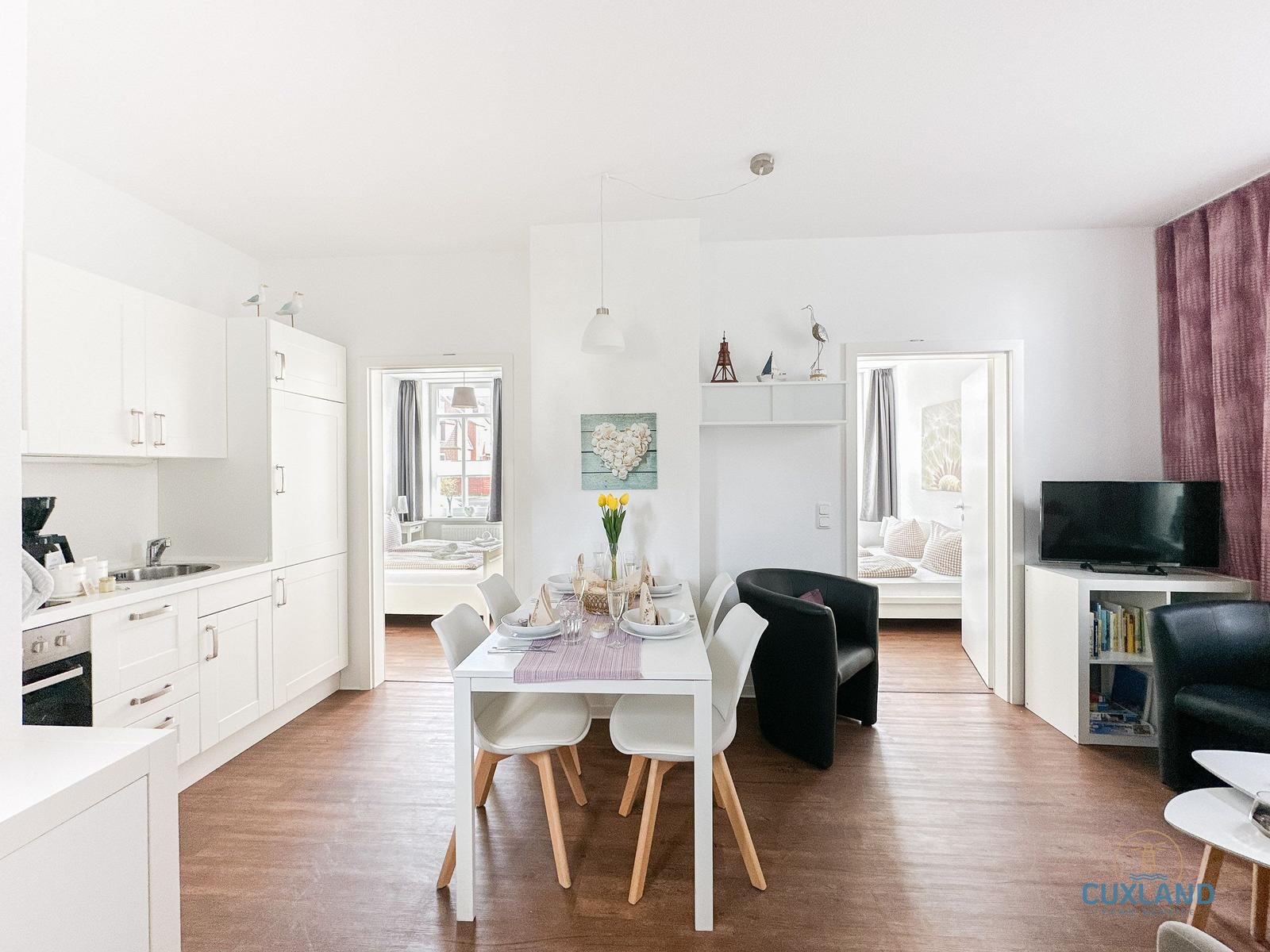 Wohnküche mit Esstisch, Schlafzimmer und Wohnbereich mit Fernseher.