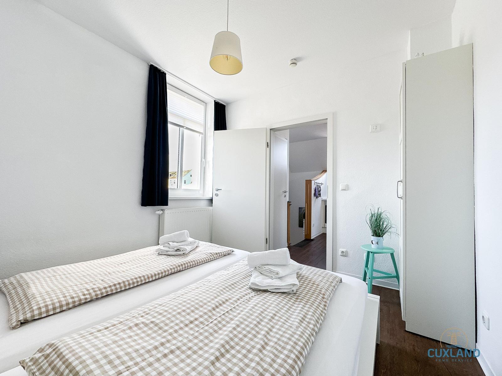 Schlafzimmer mit Doppelbett, Fenster und Kleiderschrank.