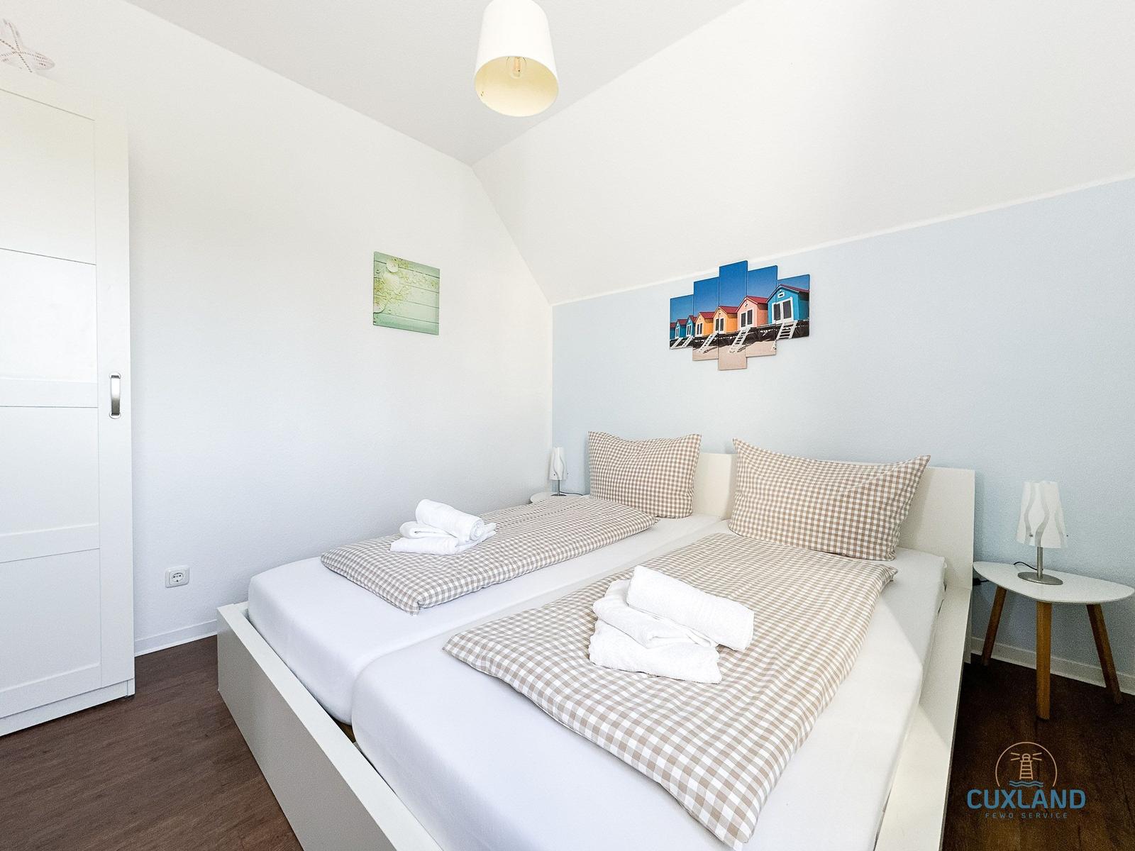 Schlafzimmer mit Doppelbett, Kissen und Bettwäsche. Wandbild und Nachttisch.