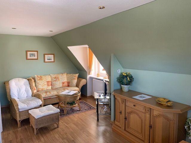 Living room with seating, cabinet, and window under sloped ceiling.