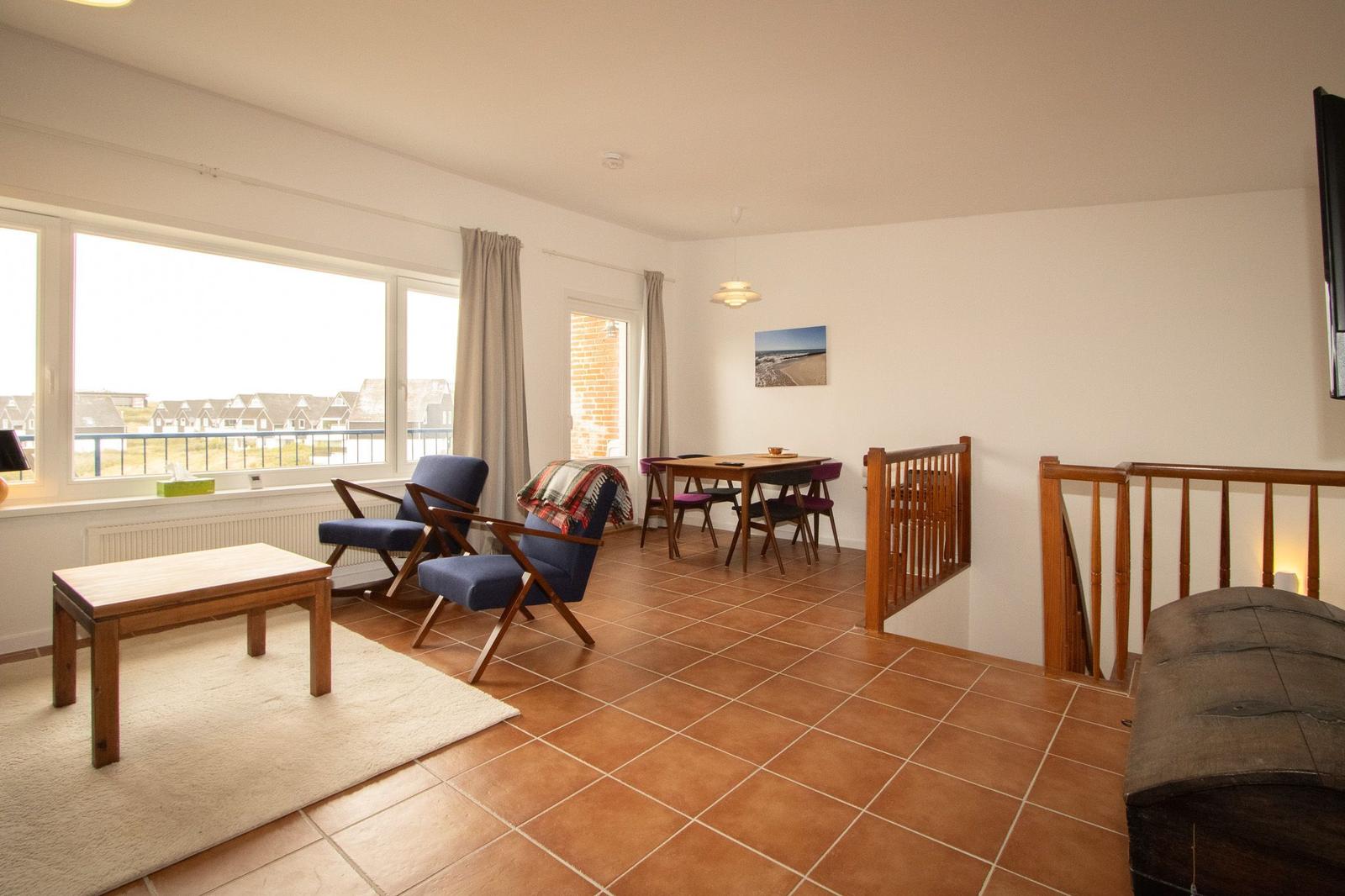 Living and dining area with wooden table, chairs, and view of the terrace.