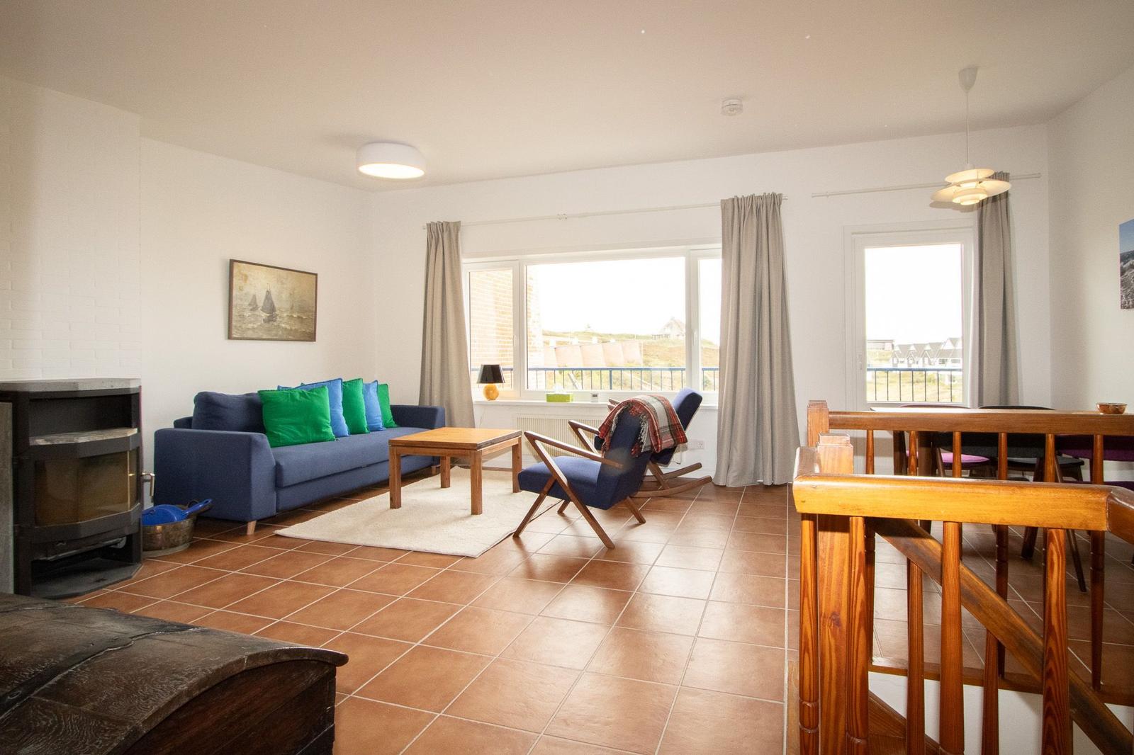 Living room with sofa, chair, and dining table. View to balcony.