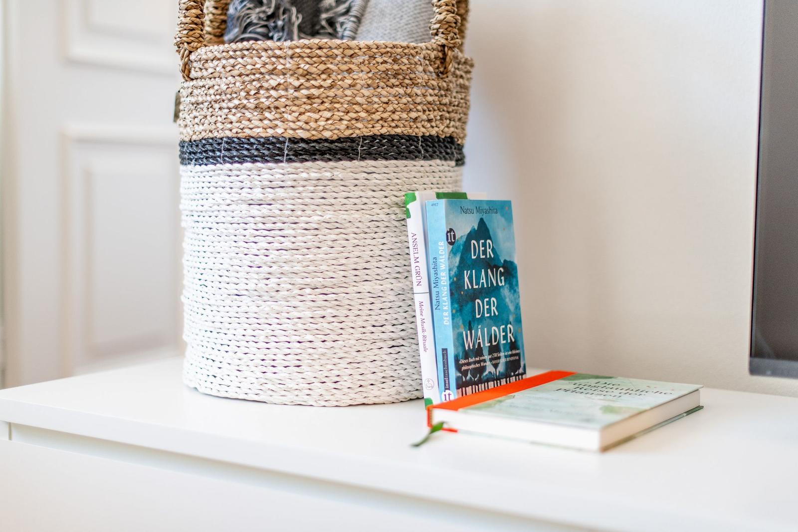 A basket and books are on a white surface.