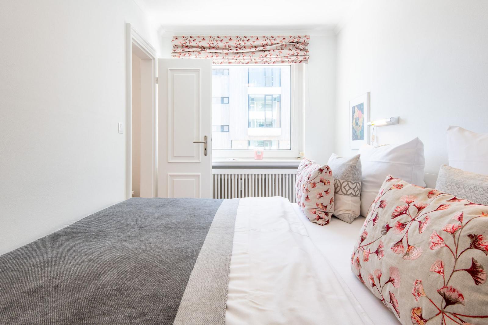 Bedroom with bed, window, and decorative pillows.