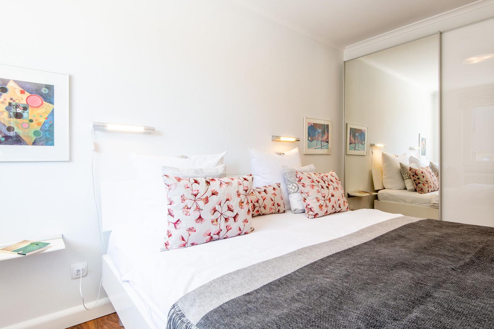 Bedroom with bed, pillows, and mirrored wardrobe on the wall.