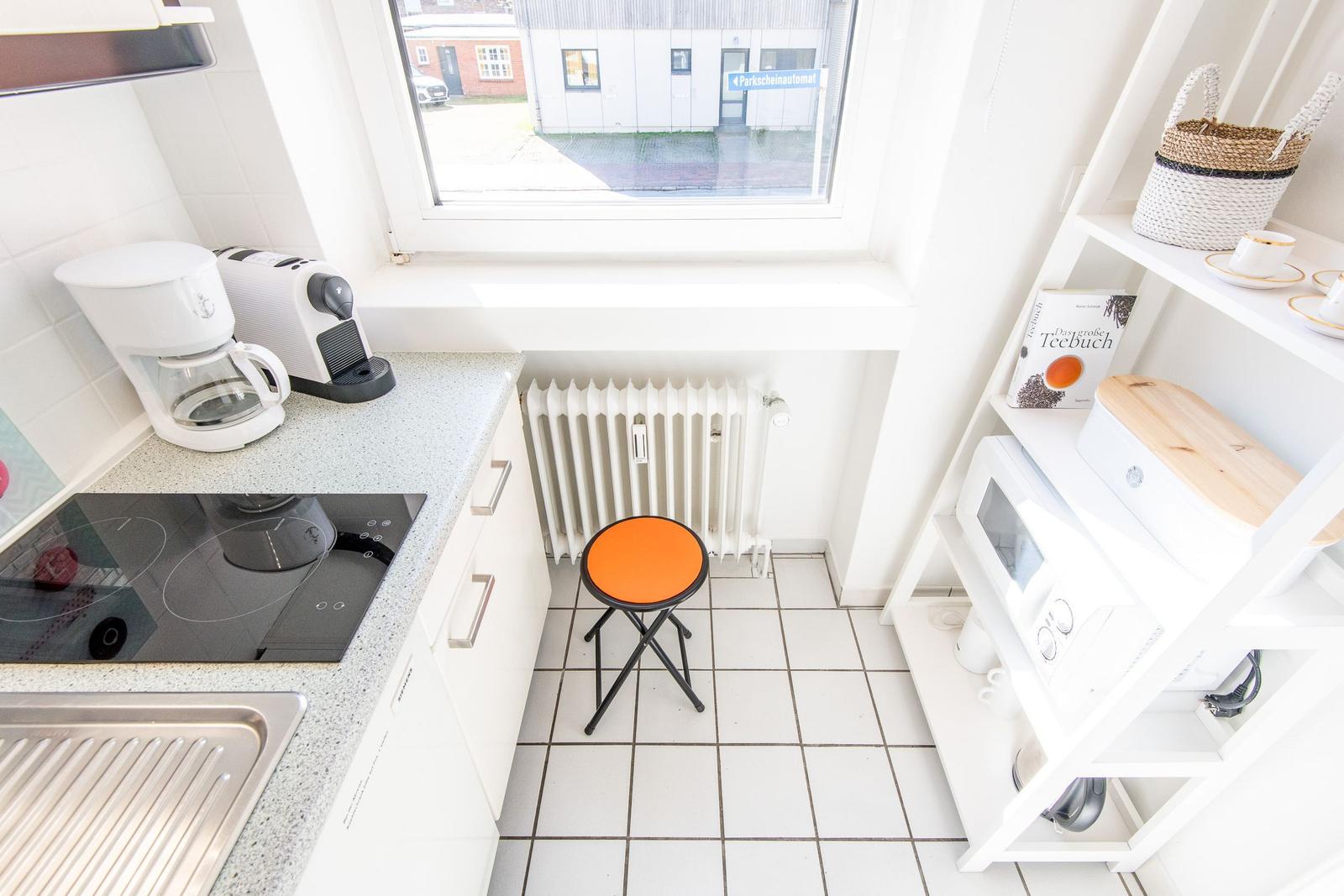 Kitchen with worktop, stove, coffee machine, and chair by window