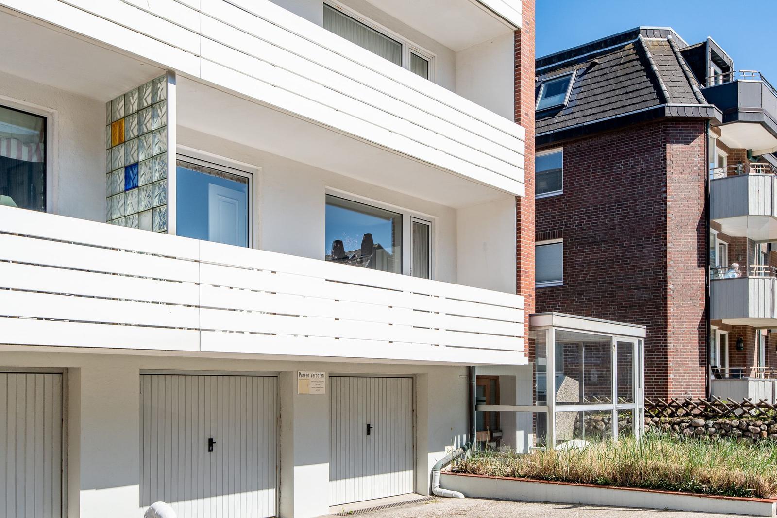 Modern apartment with balcony and garage area in urban surroundings.