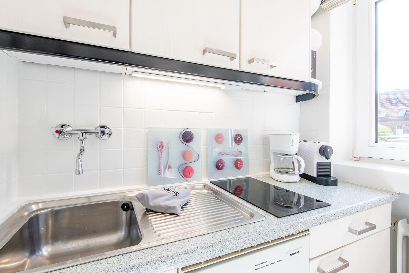 Kitchen with sink, induction cooktop, and coffee machine.