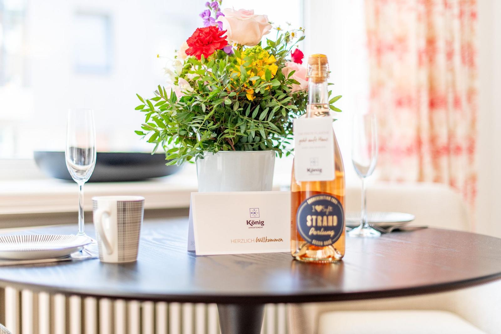 Table with flowers, wine bottle, and welcome card.
