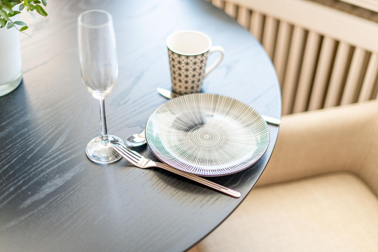Round table with plate, fork, coffee cup, and champagne glass.