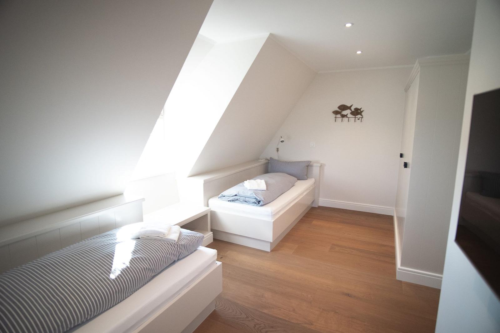 Zimmer mit zwei Betten unter Dachschrägen und Holzboden