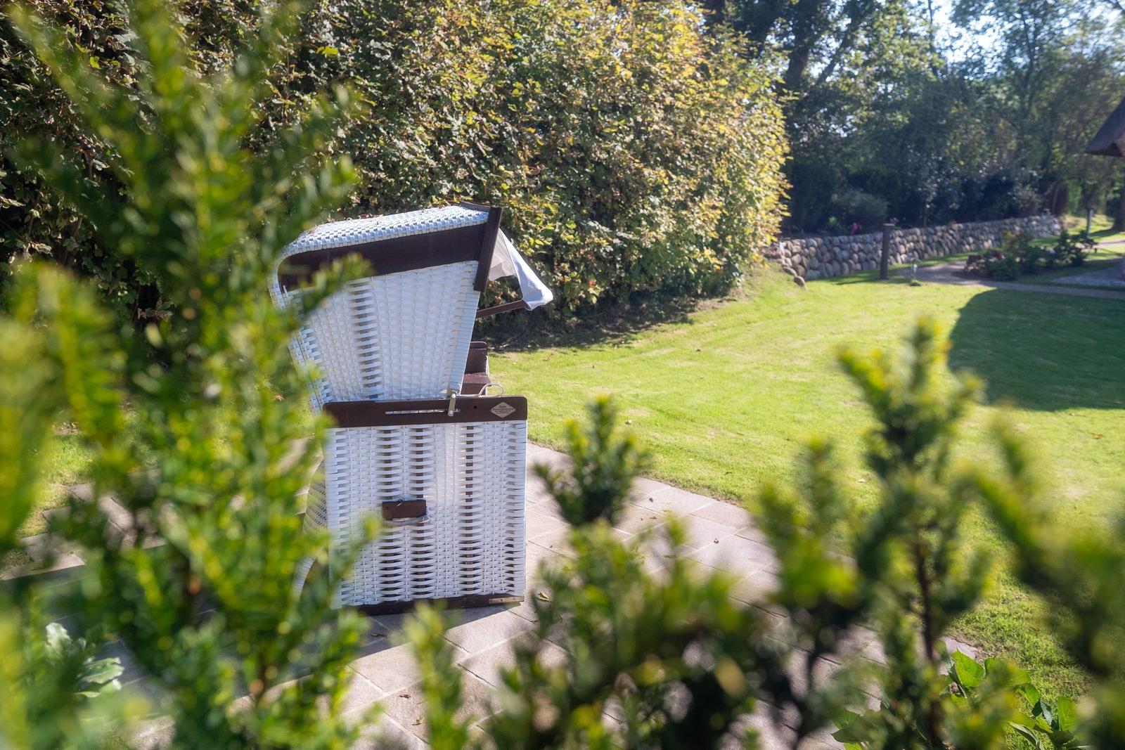 Weißer Rattan-Schirmstuhl auf Steinweg im Garten