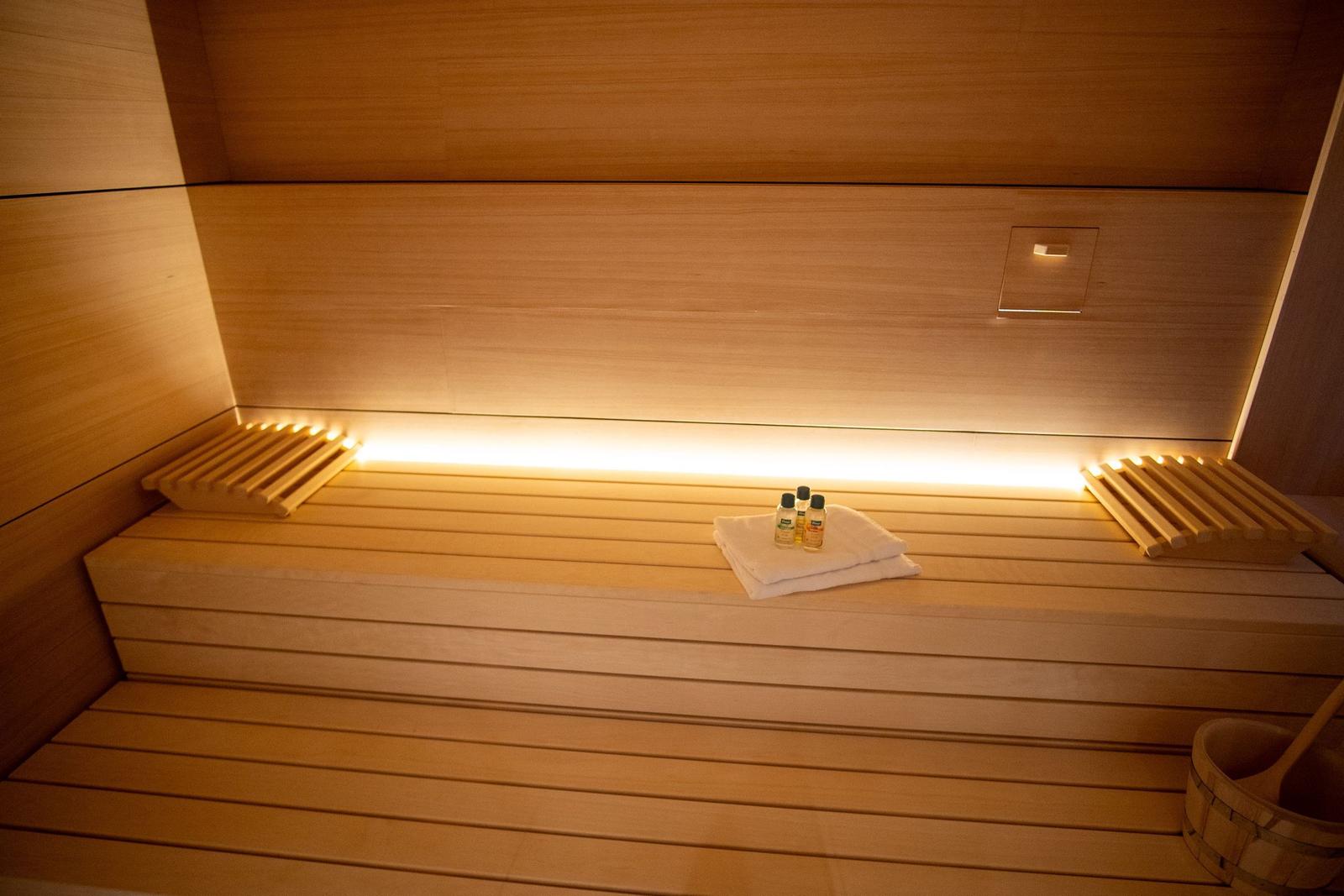 Sauna mit Holzbänken, Handtüchern und Flüssigkeiten