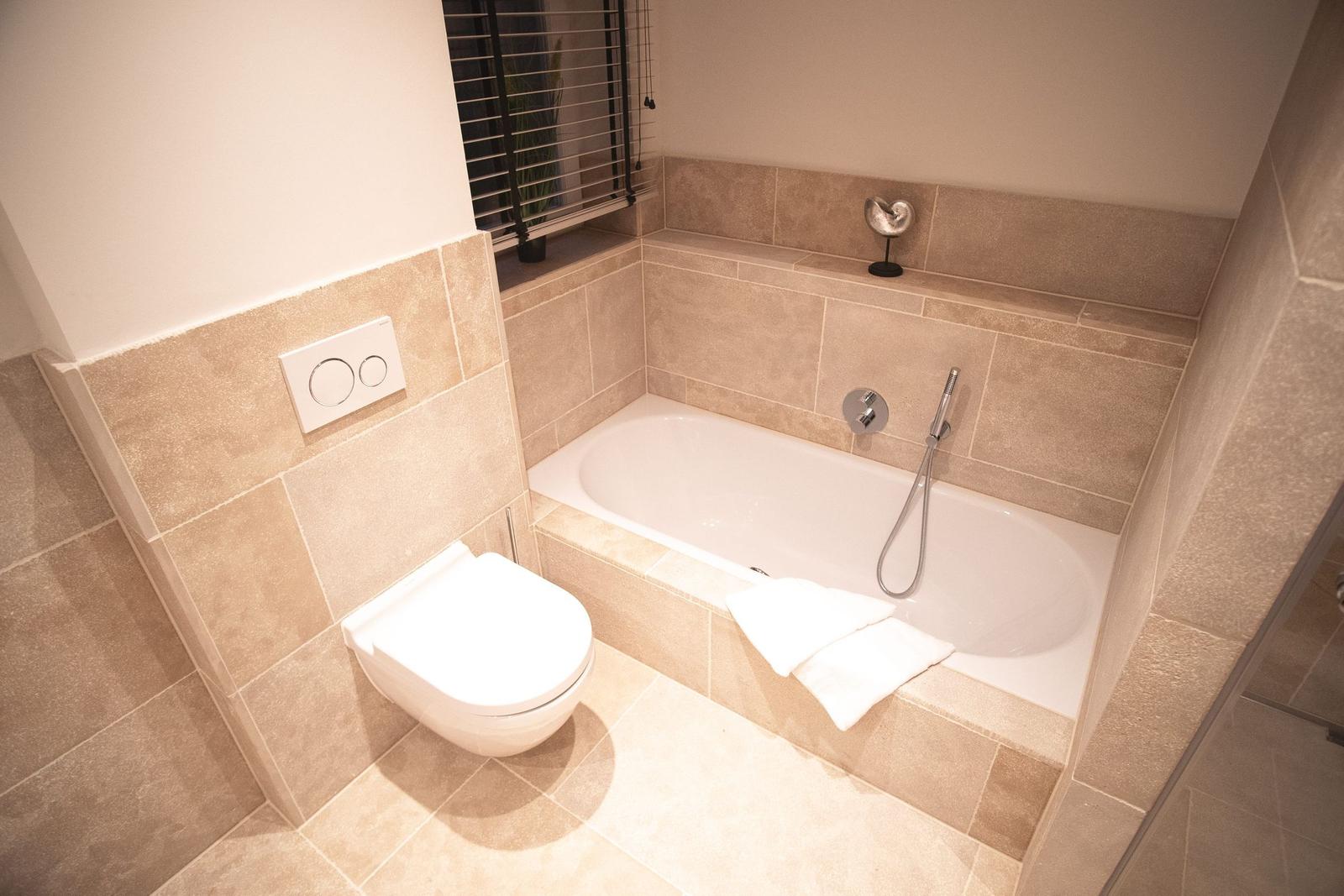 Bad mit Badewanne, Toilette und Fenster mit Jalousie