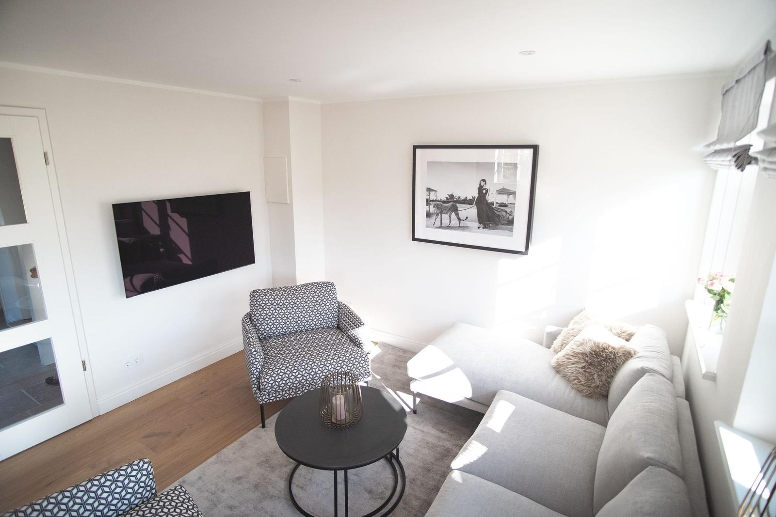 Wohnzimmer mit Sofa, Sessel, Couchtisch und Wandbild.