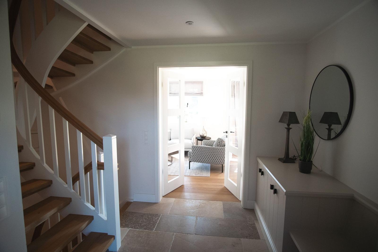 Eingang mit Treppe, Spiegel und Schrank. Durchgang zum Wohnzimmer.