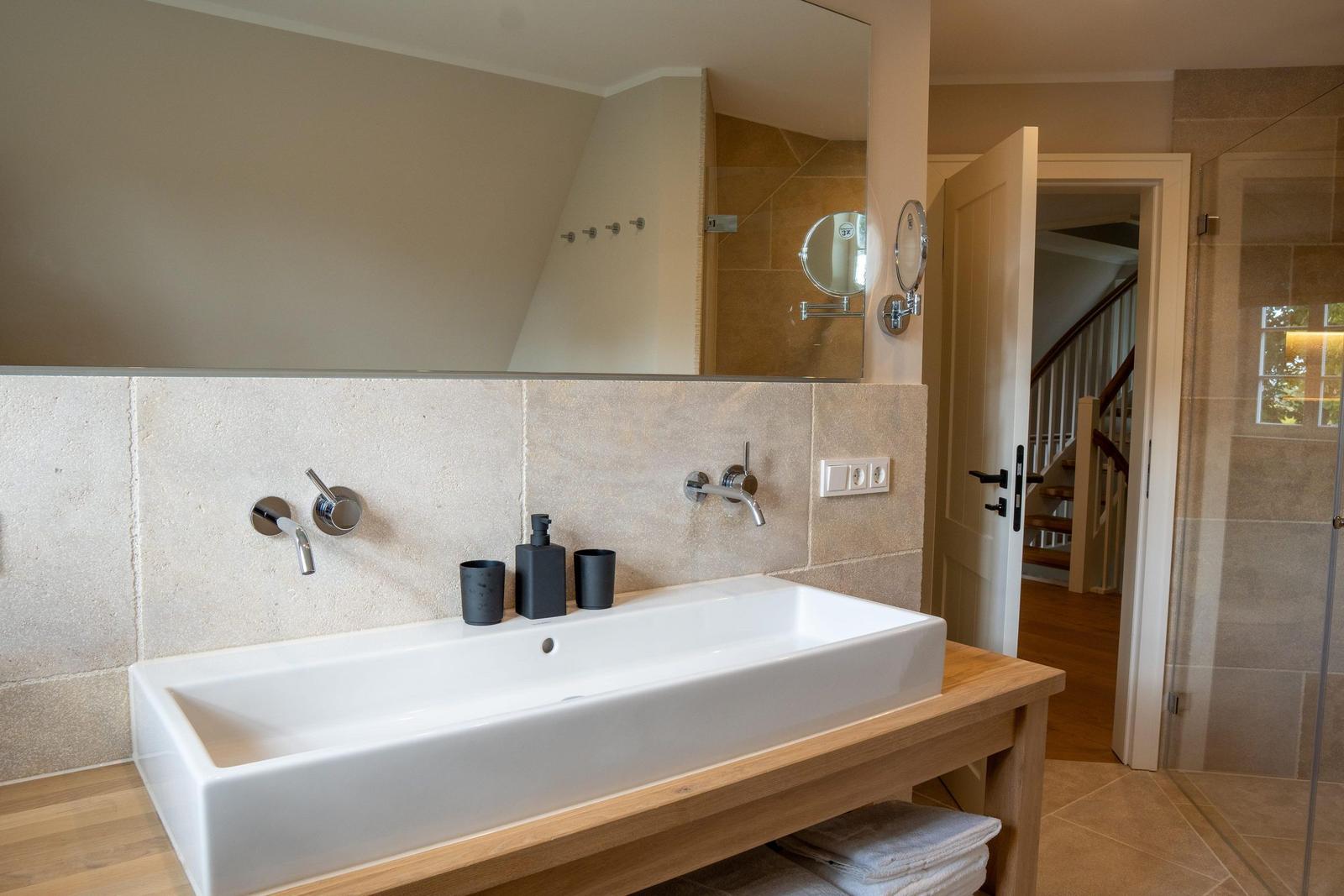 Badezimmer mit Waschbecken, Spiegel und Dusche.