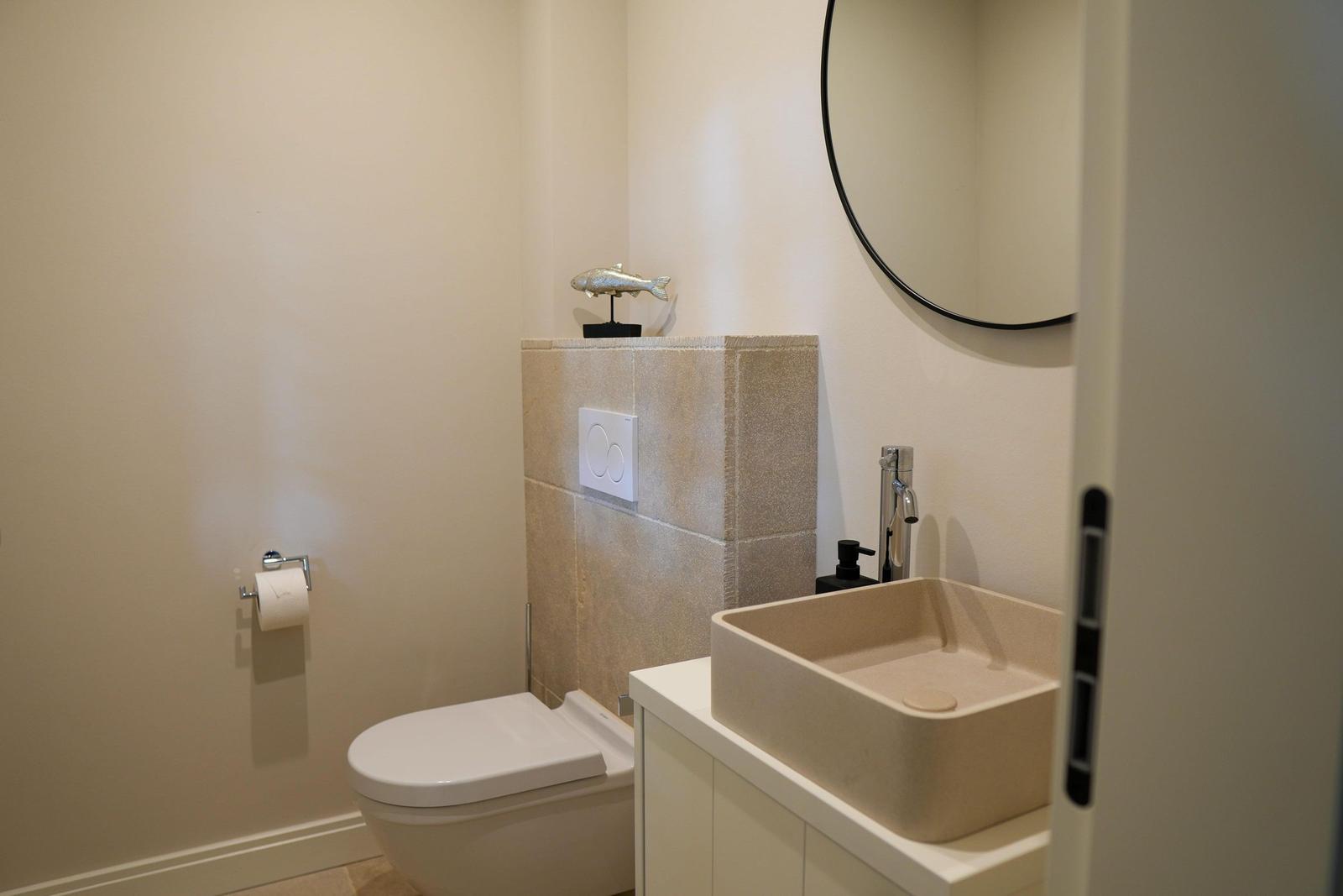 Badezimmer mit Toilette, Waschbecken und Spiegel