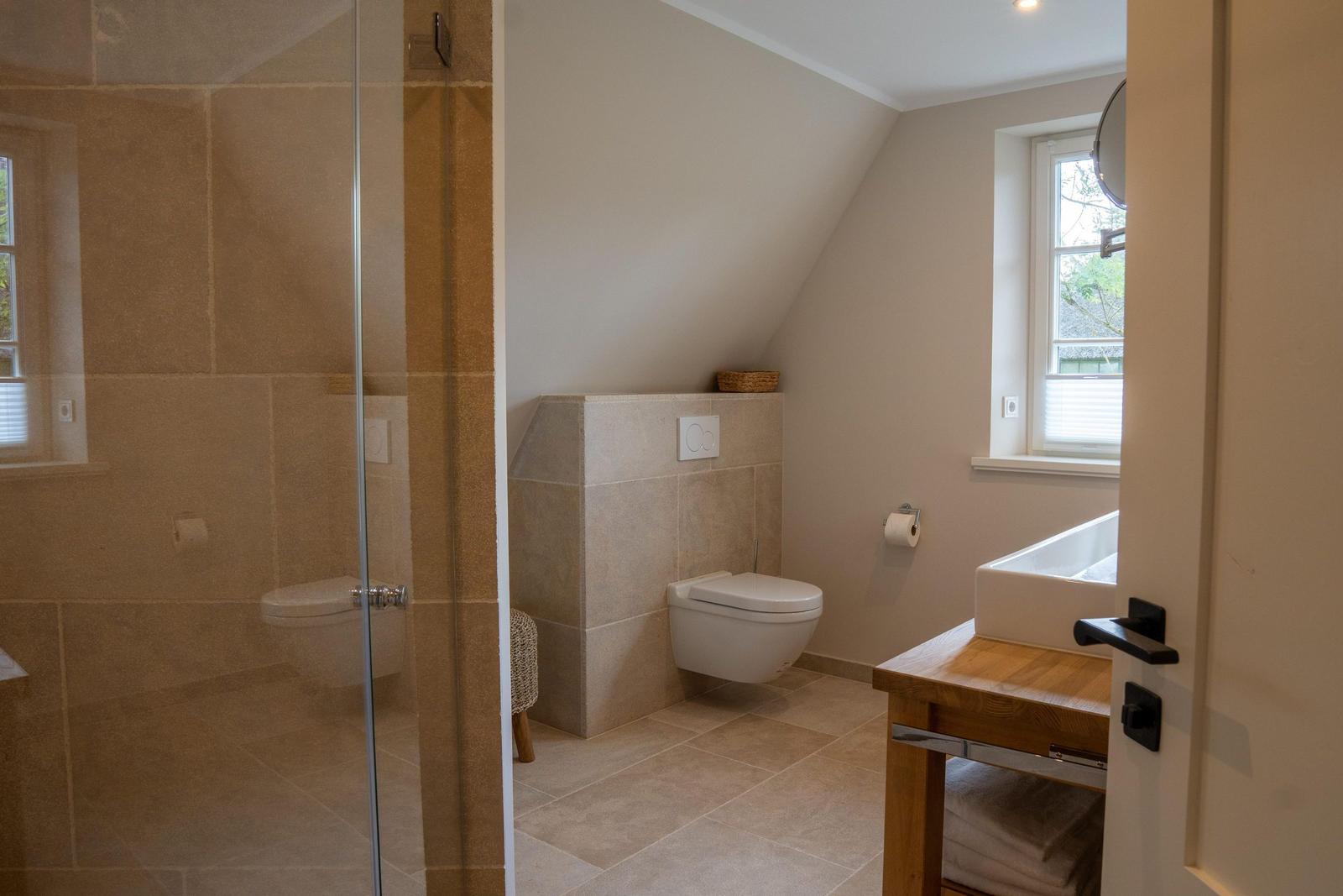 Badezimmer mit Dusche, Toilette und Waschtisch unter Dachschräge