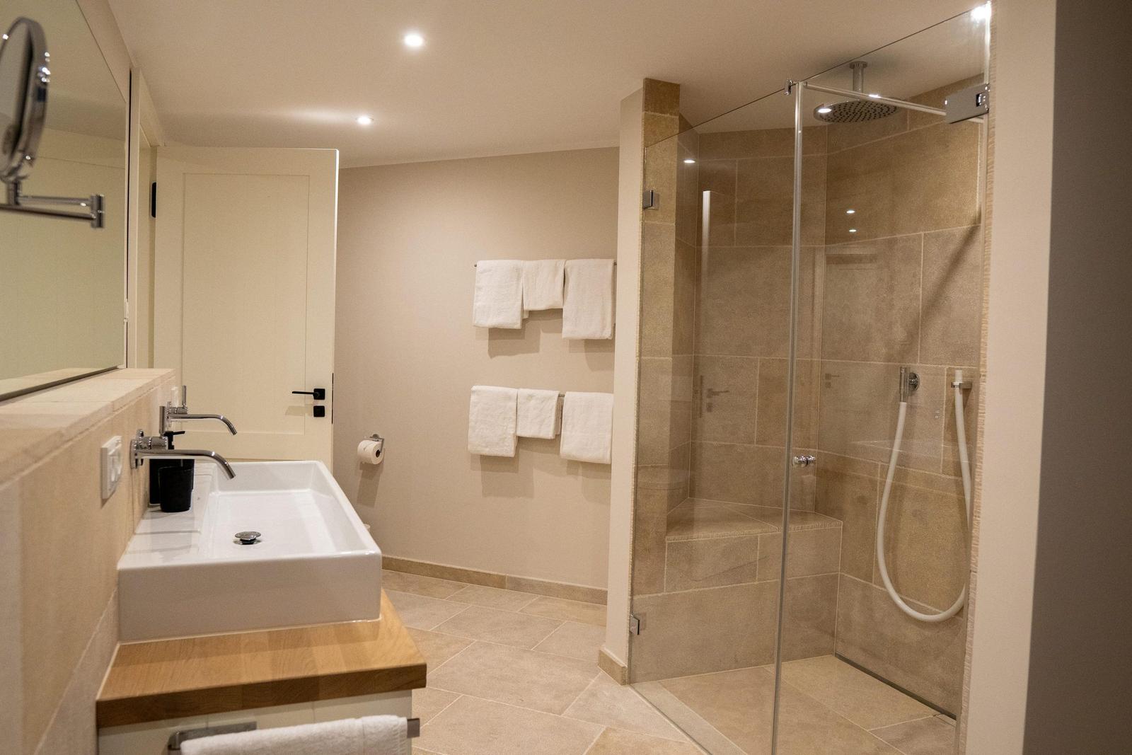 Badezimmer mit Dusche, Waschbecken und Handtüchern.